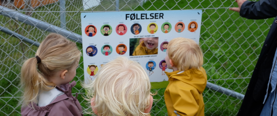 Tre børn står ved et skilt med titlen Følelser
